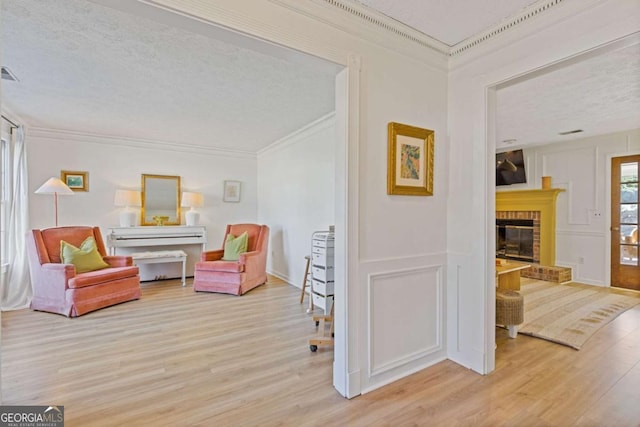 living area featuring a brick fireplace, crown molding, and wood finished floors