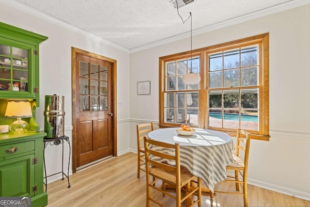 dining room featuring plenty of natural light, light wood-type flooring, crown molding, and a textured ceiling