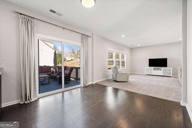 unfurnished living room featuring dark wood-style flooring, visible vents, and baseboards