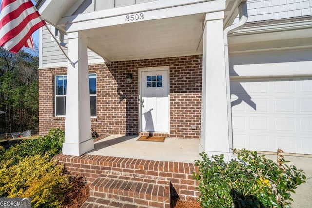 entrance to property with a porch and brick siding