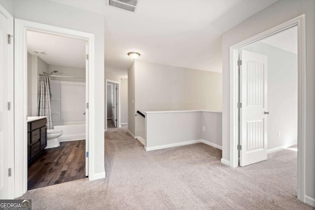 interior space featuring carpet, visible vents, and an upstairs landing