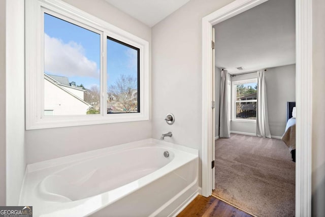 full bathroom featuring a bath and baseboards