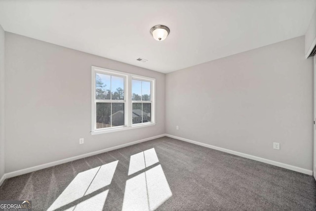 empty room featuring dark colored carpet, visible vents, and baseboards