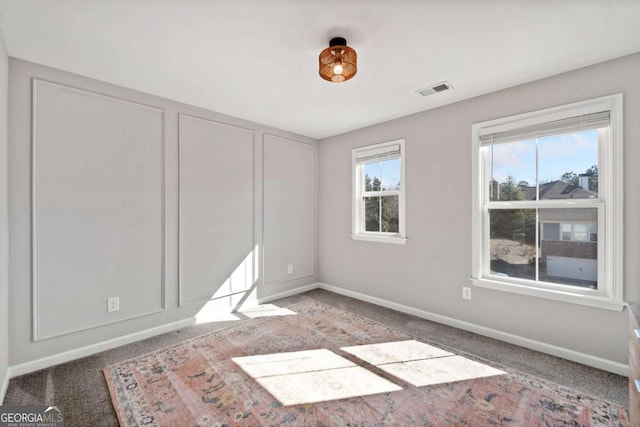 carpeted spare room featuring visible vents and baseboards