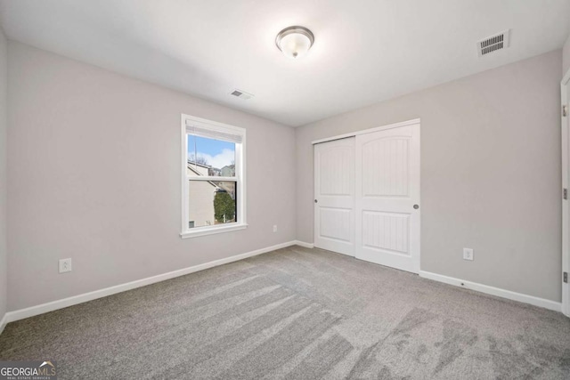 unfurnished bedroom featuring carpet floors, baseboards, visible vents, and a closet