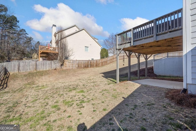 view of yard featuring fence, a wooden deck, and a patio