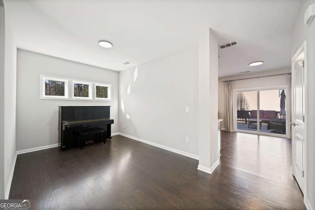 unfurnished living room featuring baseboards, visible vents, and dark wood finished floors