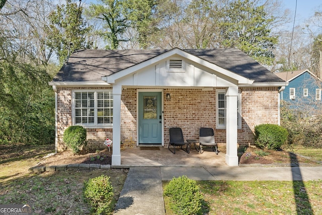 view of front of property featuring a shingled roof and brick siding