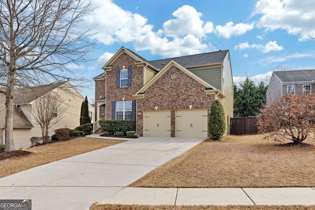 traditional-style house with a garage, brick siding, driveway, and fence