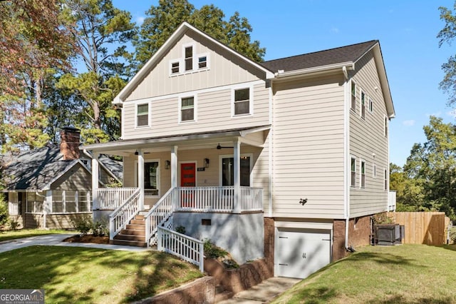 view of front of house with an attached garage, covered porch, fence, a front lawn, and board and batten siding