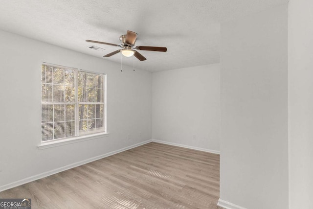 unfurnished room with baseboards, visible vents, a ceiling fan, wood finished floors, and a textured ceiling