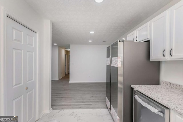 kitchen featuring a textured ceiling, stainless steel appliances, white cabinets, marble finish floor, and light stone countertops