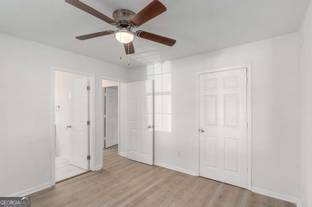 unfurnished bedroom with light wood finished floors, ceiling fan, baseboards, and connected bathroom