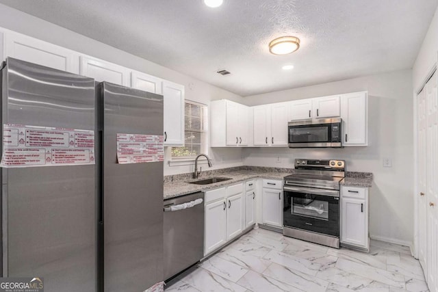 kitchen with marble finish floor, stainless steel appliances, visible vents, white cabinets, and a sink