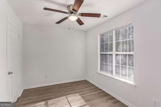 spare room with visible vents, baseboards, ceiling fan, and wood finished floors