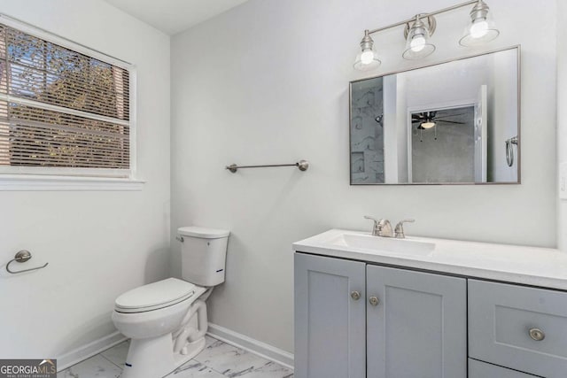 bathroom with ceiling fan, toilet, vanity, baseboards, and marble finish floor