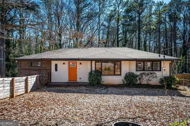 ranch-style house with brick siding, roof with shingles, and fence