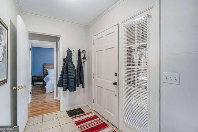 entrance foyer featuring baseboards, crown molding, and light tile patterned flooring