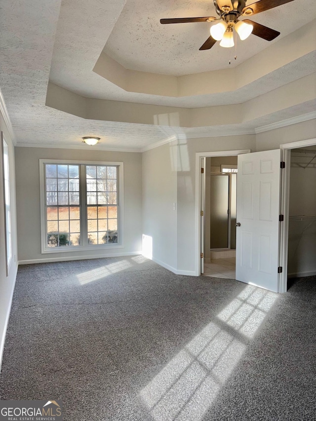 carpeted empty room featuring baseboards, a textured ceiling, a tray ceiling, and crown molding