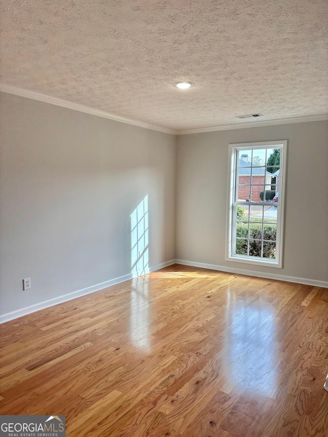 unfurnished room with a textured ceiling, ornamental molding, light wood-type flooring, and baseboards