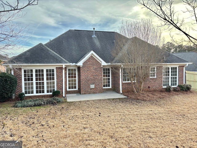 back of property with roof with shingles, fence, a yard, a patio area, and brick siding