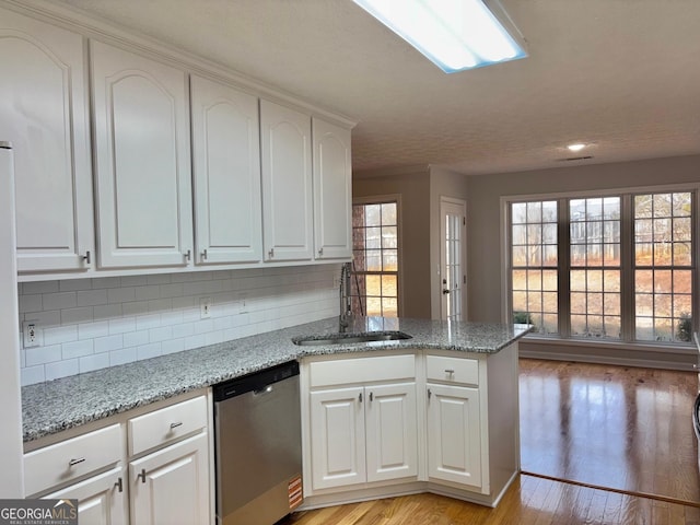 kitchen featuring a sink, white cabinets, light stone countertops, dishwasher, and light wood finished floors