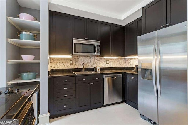 kitchen featuring stainless steel appliances, dark countertops, a sink, and open shelves