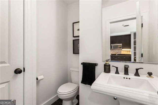 bathroom with toilet, visible vents, and a sink