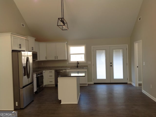 kitchen featuring a center island, dark countertops, hanging light fixtures, appliances with stainless steel finishes, and white cabinetry