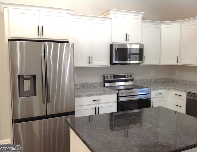 kitchen with appliances with stainless steel finishes, white cabinets, dark stone countertops, and a center island