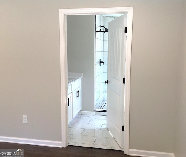 bathroom featuring marble finish floor, baseboards, and a shower