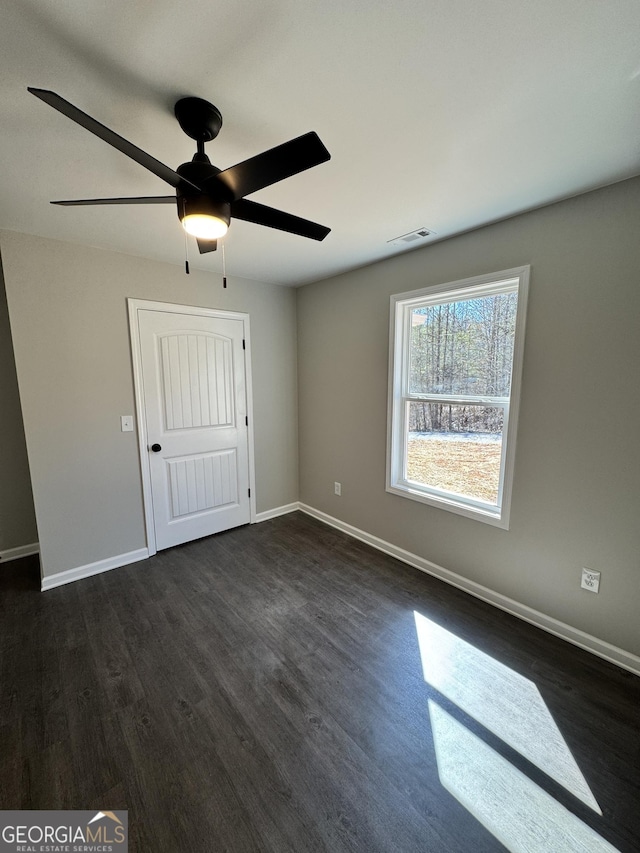 unfurnished bedroom featuring dark wood-style flooring, visible vents, ceiling fan, and baseboards