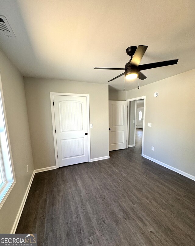 unfurnished bedroom featuring a ceiling fan, dark wood-style flooring, visible vents, and baseboards