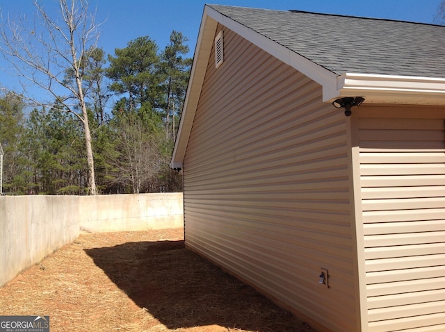 view of side of property featuring a shingled roof and a fenced backyard