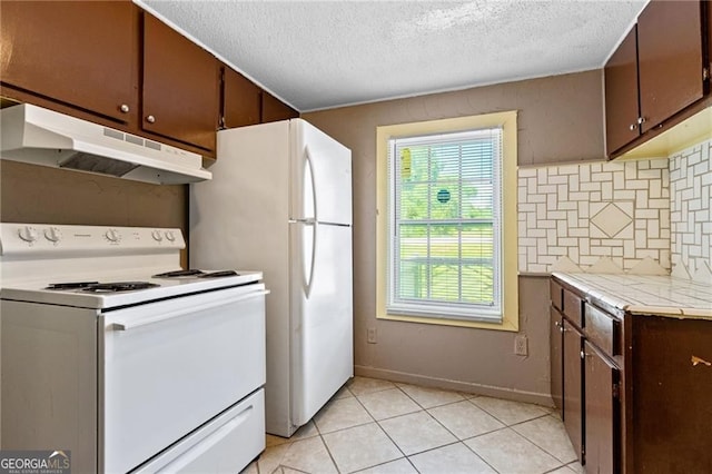 kitchen with light tile patterned floors, light countertops, backsplash, white appliances, and under cabinet range hood