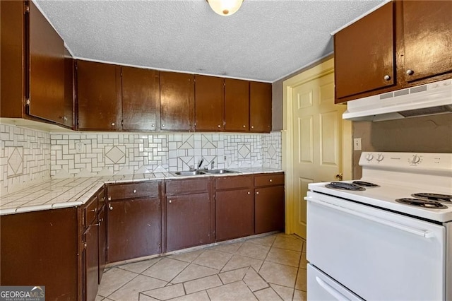 kitchen featuring white electric stove, light countertops, decorative backsplash, a sink, and under cabinet range hood