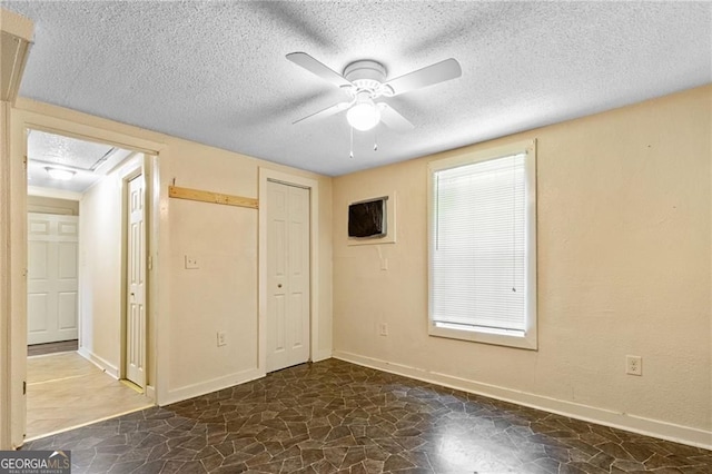 unfurnished bedroom featuring stone floors, baseboards, and a textured ceiling