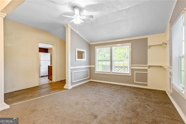 carpeted spare room featuring lofted ceiling, baseboards, a ceiling fan, and ornate columns