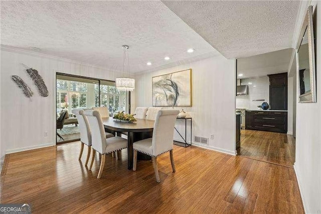 dining area featuring a notable chandelier, visible vents, hardwood / wood-style floors, a textured ceiling, and baseboards