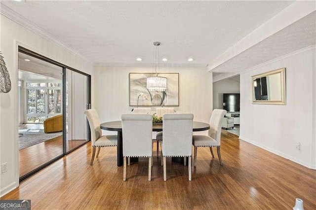 dining space featuring crown molding, a textured ceiling, baseboards, and wood finished floors