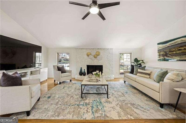 living room featuring lofted ceiling, a high end fireplace, and a healthy amount of sunlight