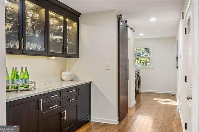 bar with recessed lighting, wood finished floors, baseboards, and a barn door