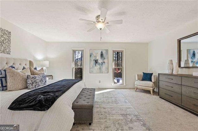 bedroom with a textured ceiling, carpet flooring, and a ceiling fan