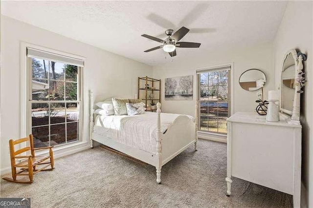 bedroom featuring light carpet, multiple windows, and a textured ceiling