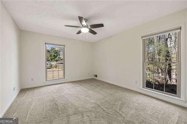 empty room with carpet flooring, ceiling fan, a textured ceiling, and baseboards