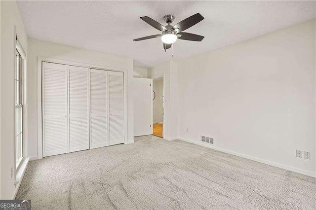 unfurnished bedroom with ceiling fan, carpet flooring, visible vents, baseboards, and a closet