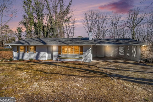 mid-century modern home featuring driveway, brick siding, a lawn, and an attached carport