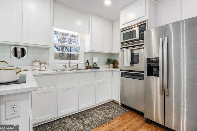 kitchen featuring a sink, white cabinets, light countertops, appliances with stainless steel finishes, and light wood finished floors