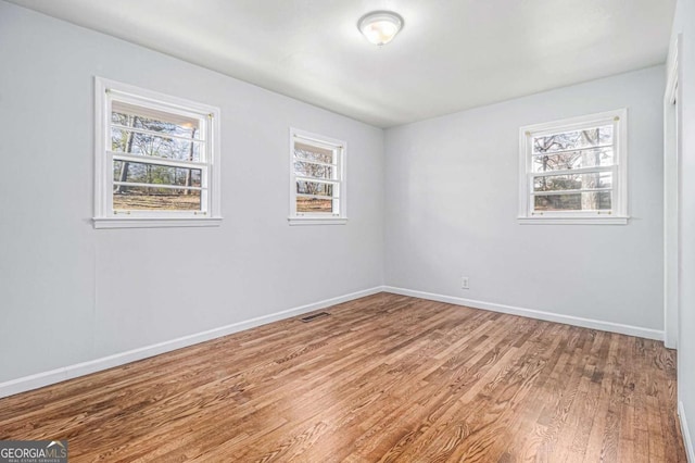 unfurnished room with light wood-type flooring, visible vents, and baseboards