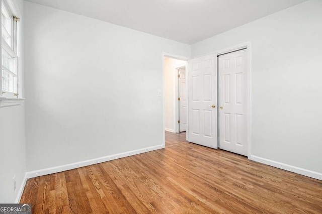 unfurnished bedroom with a closet, baseboards, and wood finished floors